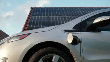 EV tip 1 kablosu olan elektrikli araba güneş panellerinin arka planında şarj bataryası, zaman aşımı. Fotovoltaik şarj istasyonundan elektrikli otomobil veya PHEV. Elektrikli araç kavramında yenilenebilir enerji