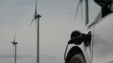 EV temiz enerji araba konsepti. Rüzgar istasyonundan gelen elektrik, EV bataryasını doğrudan sürdürülebilir elektrik jeneratörü, ilerleyen rüzgar türbini çiftliği ile şarj ediyor.