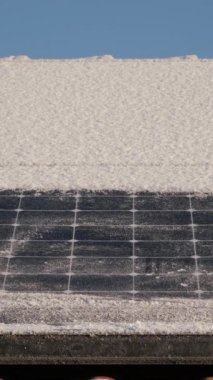 Kardan güneş panellerini temizlerken çekilmiş dikey bir video. Güneş panelleriyle elektrik alıyoruz. Kışın güneş enerjisi paneli. Tanınmayan adam güneş panellerinden kar temizledi. Kışın yenilenebilir enerji