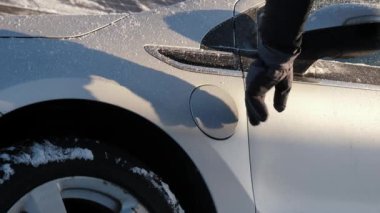 Kışın EV şarj oluyor. Eldivenli el elektrikli araca veya PHEV 'e bir güç bağlantısı yerleştirir. Tanınmayan kişi elektrik kablosunu elektrikli bir arabaya bağlar ve pilleri şarj eder.