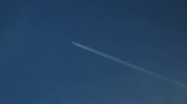 Sakin mavi bulutlu gökyüzü, gökyüzünde uçakla bırakılan soluk bir iz ile tamamlanmış sahneyi yönetiyor. Seyahatin güzelliğini ve atmosferimizin enginliğini simgeleyen uçak.