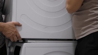 İki birey, harika sonuçlar elde etmek ve temel ev aletlerinin kurulumunun verimliliğini artırmak için takım çalışmasının önemini vurgulayarak, çamaşır ve kurutma makinesi kurmak için birlikte çalışıyor.