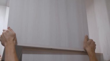 Erkek eller, modern yenileme teknikleri ve çağdaş tasarımda yüksek kaliteli materyalleri vurgulayarak, ayrıntılı iç tasarım projesi sırasında kabineyi profesyonelce duvardan uzaklaştırıyor.