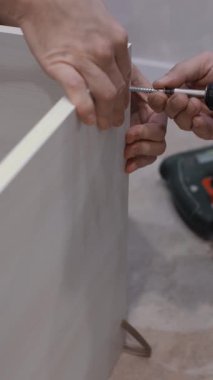 Erkek eller, DIY ev projesi için sağlam ahşap çerçeve monte etmek için elektrikli tornavida kullanır. Düzenli çalışma alanı, ev gelişiminde sanatçılık ve zanaatkarlığı vurguluyor, dikey video