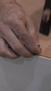 Ahşap bir panele çivi çakan yetenekli bir zanaatkarın yakın çekimi. Marangozluğa olan bağlılığı ve tutkuyu yansıtan etkileyici teknikler ve zanaatkarlığın bir göstergesi.