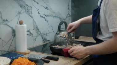 Modern mutfakta, yetenekli aşçı kıymayı karıştırıyor, lezzetli yemekler hazırlarken etkileyici mutfak becerileri sergiliyor. Sıcak atmosfer deneyimi güçlendirir, onu enfes bir yemek alanı yapar.