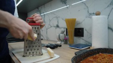 Metal rendeleyiciyle peynir rendelemek, modern bir mutfakta sağlıklı malzemelerin hazırlanmasını sergilemek...