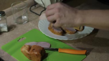 Yetenekli aşçı lezzetli bir yemek yapmak için sandviçin üzerine yumuşak füme hindi koyar.