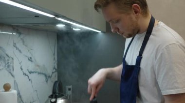 Yetenekli şef kıyma pişirir, modern mutfakta lezzetli yemekler hazırlarken etkileyici aşçılık becerileri sergiler. Sıcak atmosfer deneyimi güçlendirir, onu enfes bir yemek alanı yapar.