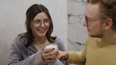 Sıcak ve cezbedici sahne, bardaklı bir çifti kahvelerinin tadını çıkartırken, sıcak bir gülümseme ve güzel dekore edilmiş bir mekanda samimi anlar paylaşırken resmediyor, romantik temalar için ideal.