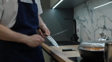 Tanınmayan profesyonel şef mutfak ortamında bıçaklarını biler, mutfak hazırlıkları ve mutfak aletleri sanatını gözler önüne serer.