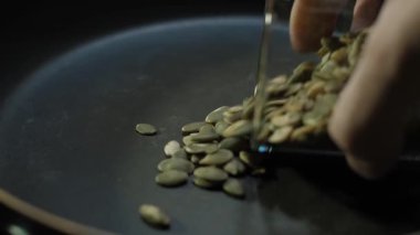 Bu, tavada çiğ kabak çekirdeği kızartma sürecini gösteren detaylı bir yakın çekim sekansı. Çeşitli yemekler için lezzetli ve sağlıklı malzemelerin nasıl hazırlandığını gösteriyor.