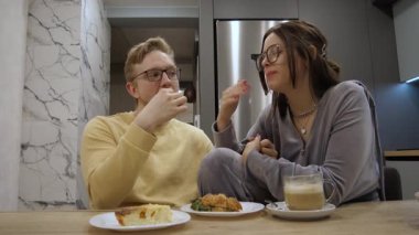 Evde samimi bir akşam yemeği, gözlüklü sevgi dolu bir çift lezzetli yiyecekler ve neşe dolu kahkahalar paylaşıyor, güzel dekore edilmiş bir mutfak ortamında derin bağlantılarını gösteriyorlar, birlikte mükemmel bir akşam.