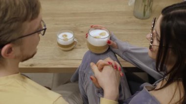 Bardaklı çift, derin bağlarını ve aşklarını vurgulayan bir fincan kahve eşliğinde hassas anların tadını çıkarırlar. Sıcak atmosfer yaratan güzel bir romantizmdir.