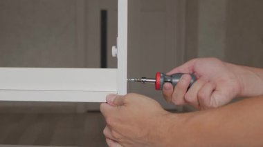 A skilled handyman uses a screwdriver to remove a screw from a shelf and repair furniture, demonstrating detailed woodworking techniques and the satisfaction of working with his hands