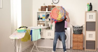 Çocuk çamaşır yıkarken kıyafetlerle oynuyor. Genç çocuk çamaşır sepeti fırlatıyor..