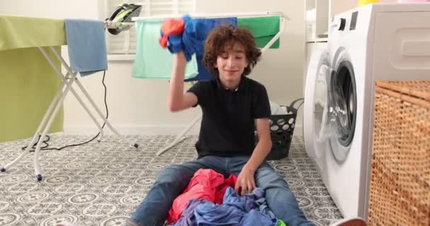 洗濯機付きの洗濯室で幸せなティーン男の子 — ストック動画