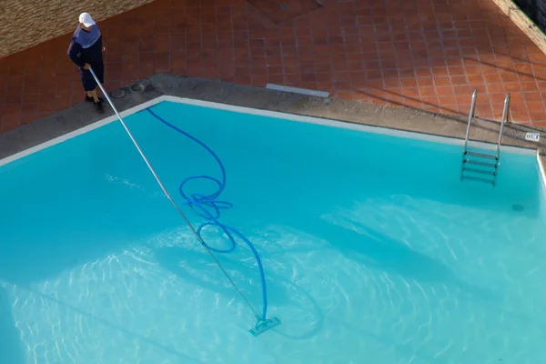 Man cleaning the swimming pool with vacuum equipment. swimming pool cleaning. a man is cleaning the pool. service care.