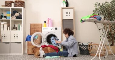 Ev işi. Çocuk evde çamaşır yıkıyor çamaşır makinesine çamaşır yüklüyor ve köpekle oynuyor.