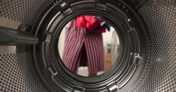 从洗衣机的内部看 一个男人把一个有色的洗衣机放进洗衣机 — 图库视频影像