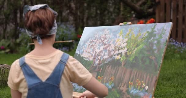 クリエイティブガールは キャンバスを作成するためのツールを使用して パレットやブラシを保持し 庭で美しい絵を描いています アーティストとアートワークのコンセプト — ストック動画