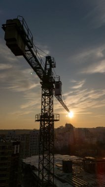 Gün batımında şehrin ufuk çizgisinde inşaat alanında kule vinci