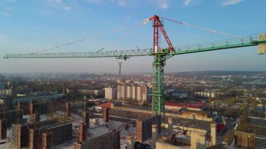 Arka planda şehrin silueti olan yüksek binalı inşaat alanında faaliyet gösteren bir vinç.