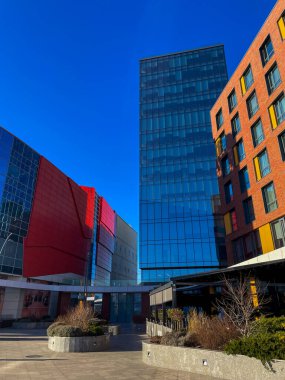 Mavi gökyüzünün altında cam ve tuğla binaları olan modern şehir mimarisi