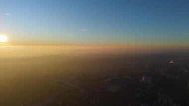 Gün batımında altın sisli bir şehrin insansız hava aracı görüntüsü