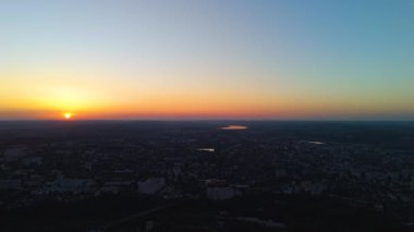 Hava aracı görüntüsü sol tarafta şehrin üzerinde gün batımını izliyor
