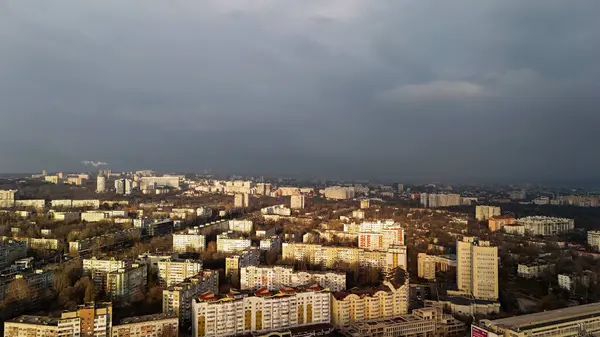 Altın güneş ışığı ve kara fırtına bulutlarıyla dolu havadan bir şehir.