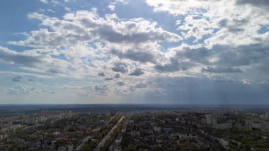 Gökyüzü şehri manzarası. Binaların üzerinde güneş ışığı ve bulutlar var.