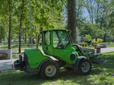 Şehir parkında sıkıştırılmış yeşil yükleyici makinesi