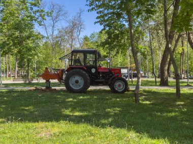 Şehir parkına park etmiş kırmızı traktör.