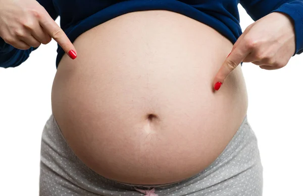 8ヶ月の妊娠の概念として白い背景に隔離された彼女のおなかを指している将来のお母さんのクローズアップ — ストック写真