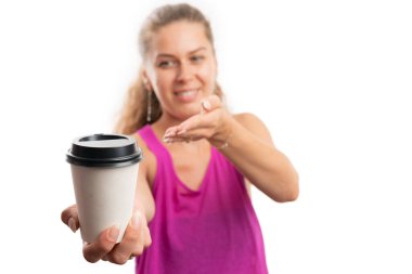 Fit adult woman smiling wearing pink gym tanktop for workout presenting close-up of paper coffee cup as morning fitness concept isolated on white studio background