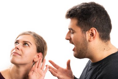 Adult girlfriend making listening gesture with hand to ear while boyfriend yelling talking as relationship communication concept isolated on white studio background