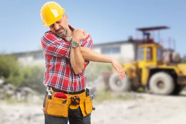 Tired male worker stretching his arms at workplace after hard work