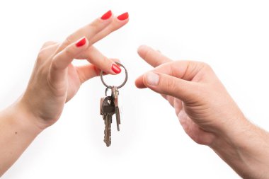 Satıcı elden ev anahtarlarını alan manken kişi emlakçı konsepti olarak beyaz stüdyo arka planında izole edilmiş.