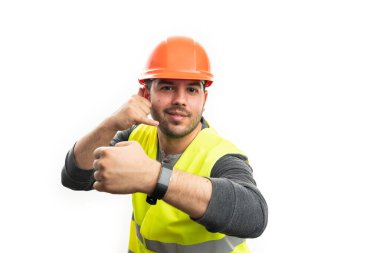 İnşaatta çalışan neşeli yetişkin inşaatçı, beyaz stüdyo arka planında izole edilmiş akıllı kol saatini gösteren bir telefon hareketi yapıyor.