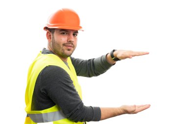 Turuncu şapka ve floresan yelek giyen, dost canlısı gülümseyen, beyaz arka planda izole edilmiş palmiyeler arasındaki küçük nesne boşluğunu temsil eden adam.