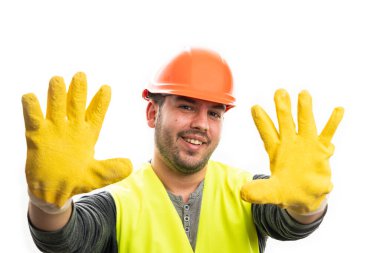 Gülümseyen neşeli erkek müteahhit, beyaz arka planda izole edilmiş koruyucu ekipman olarak sarı iş eldivenleri ve yelek giymiş ellerini sunuyor.