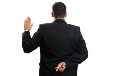 Yetişkin bir işadamı, elini arkasını dönük tutarak sahte yemin jesti yapıyor. Beyaz stüdyo arka planında izole edilmiş sahtekar bir konsept.