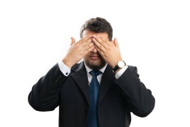 Kurumsal iş adamı, beyaz arka planda izole edilmiş gizli bir körlük konsepti olarak gözleri kaplayan şık bir takım elbise giyiyor.