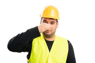 Erkek inşaat işçisi burnuna kötü koku konsepti olarak sahip. Beyaz stüdyo arka planında izole edilmiş iş ekipmanları giyiyor.