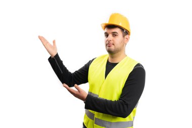 Sarı iş kıyafetli yetişkin erkek müteahhit beyaz stüdyo arka planında avuç içi avuçlarıyla reklam için boş telif alanı sunuyor.