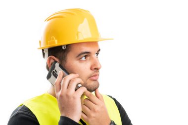 Sarı koruyucu kask ve yelek giyen yetişkin inşaat işçilerinin yakın plan görüntüleri beyaz stüdyo arka planında izole edilmiş telefonla konuşmaları.