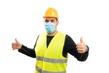 19 virüslü grip salgını için cerrahi tek kullanımlık maske takan adam beyaz stüdyo arka planında izole edilmiş iki baş parmak hareketi yapıyor.