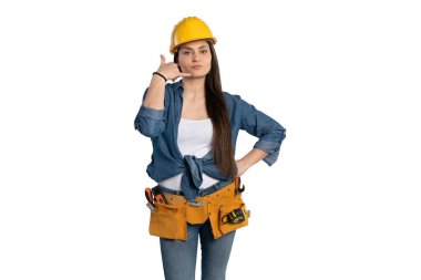 Sarı sapkalı ve kot gömlekli kendine güvenen bir inşaat işçisi, eliyle bir telefon sembolü yaparak 