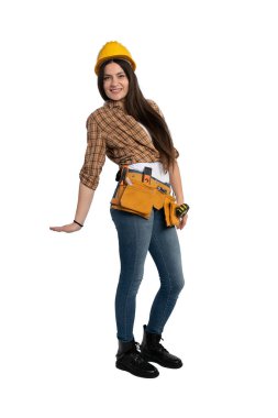 Ekose gömlek ve alet kemeri takmış, kendinden emin bir şekilde gülümseyen kadın inşaat işçisi. Rahat ve dost canlısı profesyonel görünüş, inşaat, işçilik ve kalifiye ticaret temaları için ideal